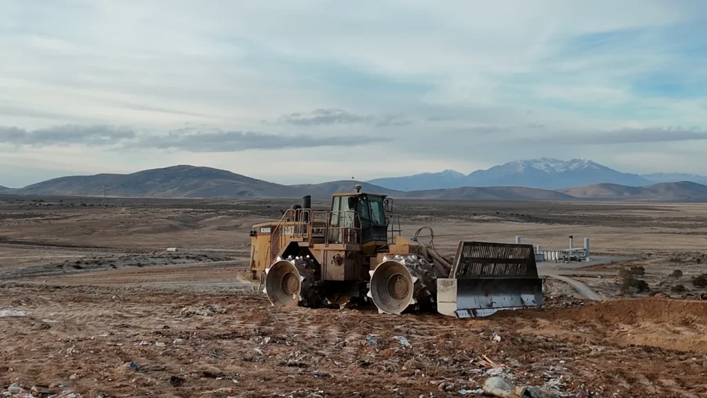 A Caterpillar 836G landfill compactor parked on freshly covered ground at Bayview Landfill, with gas collection wellheads visible in the background.